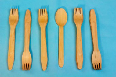 Açık mavi arka plan üzerinde tek kullanımlık ekolojik ahşap bambu çatal desen. Çevre dostu düz metin için ücretsiz kopyalama alanı ile yatıyordu. Seçici arka plan