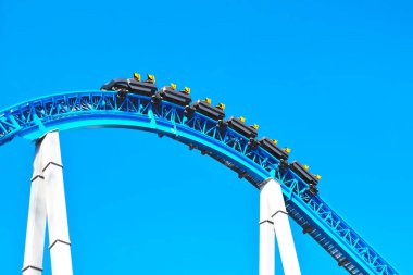 Mavi ürkütücü korkunç roller coaster tatil hafta sonu eğlence parkı döngü ve sarı koltuklar ile hızlı sürme. İnsanlar olmadan boş roller coaster