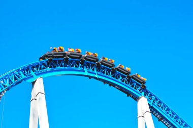 İnsanlar dinlenmek, eğlenmek ve hızlı tatil hafta sonu eğlence parkı döngü ile mavi ürkütücü korkunç roller coaster binmek. Rollercoaster hareket le bulanık
