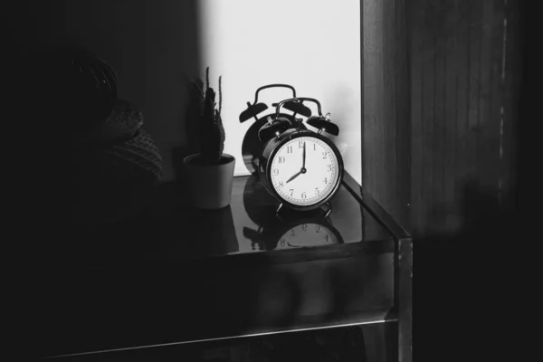 ハードシャドウを持つ夕日の光線で磨かれた表面に反射と木製のベッドサイドテーブル上の黒いレトロなヴィンテージ目覚まし時計 — ストック写真