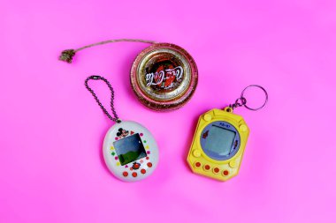 Saint-Petersburg, Rusya - 27 Mart 2019: Eski retro oyun tamagotchi ve yo yo oyuncak etiketi ile coca-cola pembe arka plan, 90'lardan sanal evcil hayvan oyuncak. açıklayıcı Editoryal