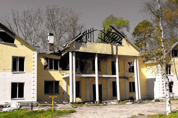 Burnt down after fire large country house with a collapsed damaged roof against a grey sky. burnt down large country house with a collapsed damaged roof against a grey sky