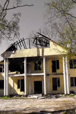 Yangından sonra yanan büyük bir kır evi gri gökyüzüne karşı çökmüş hasarlı çatı ile. gri bir gökyüzüne karşı çökmüş hasarlı çatı ile büyük bir kır evi yandı