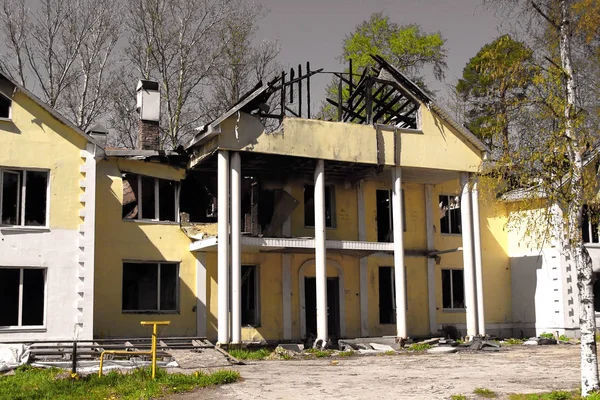 Burnt down after fire large country house with a collapsed damaged roof against a grey sky. burnt down large country house with a collapsed damaged roof against a grey sky