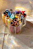 barevné nitě v průhledných plastových šicích bednech na tkaninové plátně. nástroje pro řemeslné a hobby