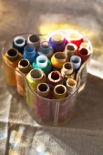 barevné nitě v průhledných plastových šicích bednech na tkaninové plátně. nástroje pro řemeslné a hobby