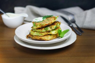 Doğru beslenme, vejetaryen kahvaltı glutensiz, fasulye ile kabak kabak krep, ekşi yunan yoğurt ile beyaz tabaklarda nane, siyah arka plan, havlu, çatal, ahşap yüzeyüzerinde bıçak