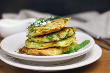 Doğru beslenme, vejetaryen kahvaltı glutensiz, fasulye ile kabak kabak krep, ekşi yunan yougurt ile beyaz tabaklarda nane, siyah arka plan, havlu, çatal, ahşap yüzeyüzerinde bıçak