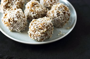 vejetaryen çiğ sağlıklı diyet hiçbir fırında şekertatlı şekersiz tatlı şekerler şeker siz ve hindistan cevizi ile glutensiz, mavi plaka ve siyah kayrak arka plan üzerinde uygun beslenme snack, metin için ücretsiz kopya alanı