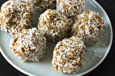 vejetaryen çiğ sağlıklı diyet hiçbir fırında şekertatlı şekersiz tatlı şekerler şeker siz ve hindistan cevizi ile glutensiz, mavi plaka ve siyah kayrak arka plan üzerinde uygun beslenme snack, metin için ücretsiz kopya alanı