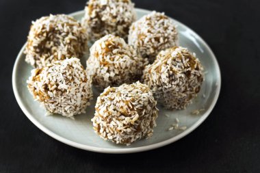 Vejetaryen ham sağlıklı diyet Hayır Bake şekerler tatlı tatlılar olmadan şeker ve gluten-ücretsiz Hindistan cevizi, mavi plaka ve siyah arduvaz arka planda uygun beslenme snack, yumuşak seçici odak