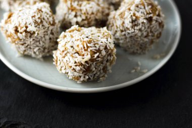 vejetaryen çiğ sağlıklı diyet hiçbir fırında şekertatlı şekersiz tatlı şekerler şeker siz ve hindistan cevizi ile glutensiz, mavi plaka ve siyah kayrak arka plan üzerinde uygun beslenme snack, metin için ücretsiz kopya alanı