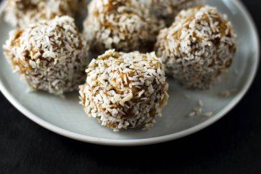 vejetaryen çiğ sağlıklı diyet hiçbir fırında şekertatlı şekersiz tatlı şekerler şeker siz ve hindistan cevizi ile glutensiz, mavi plaka ve siyah kayrak arka plan üzerinde uygun beslenme snack, metin için ücretsiz kopya alanı