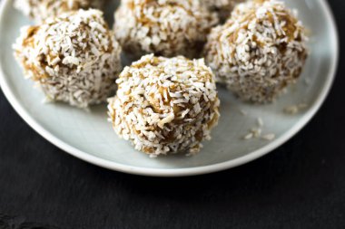 Vejetaryen ham sağlıklı diyet Hayır Bake şekerler tatlı tatlılar olmadan şeker ve gluten-ücretsiz Hindistan cevizi, mavi plaka ve siyah arduvaz arka planda uygun beslenme snack, yumuşak seçici odak