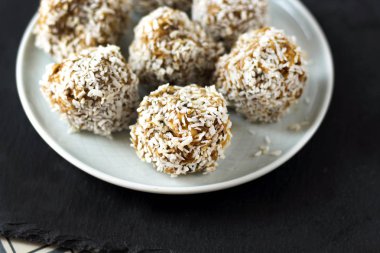 vejetaryen çiğ sağlıklı diyet hiçbir fırında şekertatlı şekersiz tatlı şekerler şeker siz ve hindistan cevizi ile glutensiz, mavi plaka ve siyah kayrak arka plan üzerinde uygun beslenme snack, metin için ücretsiz kopya alanı