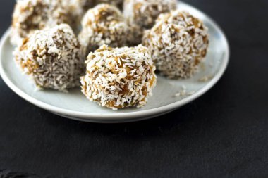 vejetaryen çiğ sağlıklı diyet hiçbir fırında şekertatlı şekersiz tatlı şekerler şeker siz ve hindistan cevizi ile glutensiz, mavi plaka ve siyah kayrak arka plan üzerinde uygun beslenme snack, metin için ücretsiz kopya alanı