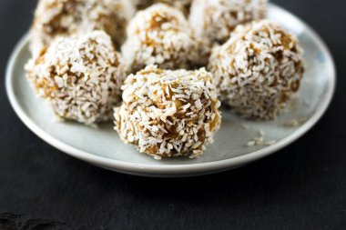 vejetaryen çiğ sağlıklı diyet hiçbir fırında şekertatlı şekersiz tatlı şekerler şeker siz ve hindistan cevizi ile glutensiz, mavi plaka ve siyah kayrak arka plan üzerinde uygun beslenme snack, metin için ücretsiz kopya alanı