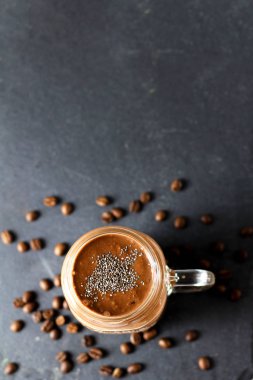Kahve çekirdekleri ile siyah bir grafit arduvaz arka planda cam kavanoz Chia tohumları ile organik doğal çikolata kahve kakao Smoothie içecek, üst görünüm. Sağlıklı diyet vejetaryen snack. Ücretsiz kopya alanı