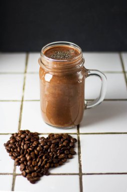 Kalp şeklinde kahve çekirdekleri ile siyah bir grafit arduvaz arka planda cam kavanoz Chia tohumları ile organik doğal çikolata kahve kakao Smoothie içecek. Sağlıklı diyet vejetaryen snack.
