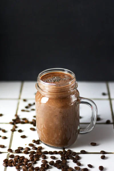 オーガニックナチュラルチョコレートコーヒーカカオスムージー飲料は コーヒー豆と黒のグラファイトのスレートの背景にガラス瓶にチア種子を入れました 健康的なダイエットベジタリアンスナック フリーコピースペース — ストック写真