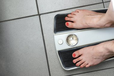 gri bir karo yakın katta analog mekanik eski retro banyo ağırlık ölçeği. Diyet kilo kontrolü. Bacaklarda kırmızı oje olan kız teraziye tartılır.