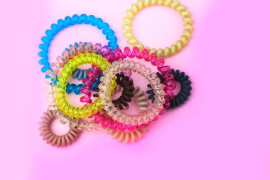 Metin için ücretsiz kopya alanı ile pembe arka plan üzerinde kadın kuaför saç modeli için plastik spiral renkli renkli scrunchies