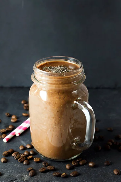 Organic natural chocolate coffee cacao smoothie beverage with chia seeds in glass jar with chocolate bar on a black graphite slate background. Healthy diet vegetarian snack. noise effect