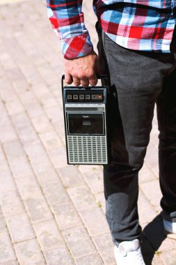 Elinde tutan ekose gömlek Hipster fantezi adam ve retro vintage eski 80s ile yürüyüş , 90s tarzı taşınabilir radyo ses kaset kaydedici çalar boombox içinde ses kaseti ile 