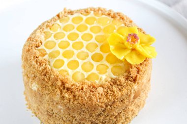 Rus katmanlı bal kek medovic tatlı beyaz ahşap tepsi üzerinde çikolata petek ve tereyağı krem şekli narcissus çiçek ile süslenmiş ahşap bal kaşığı yanında tatlı. doğum günü partisi kutlaması