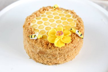 Rus katmanlı bal kek medovic tatlı beyaz ahşap tepsi üzerinde çikolata petek ve tereyağı krem şekli narcissus çiçek ile süslenmiş ahşap bal kaşığı yanında tatlı. doğum günü partisi kutlaması