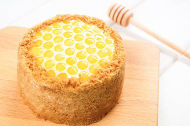 Rus katmanlı bal kek medovic tatlı beyaz ahşap tepsi üzerinde çikolata petek ve tereyağı krem şekli narcissus çiçek ile süslenmiş ahşap bal kaşığı yanında tatlı. doğum günü partisi kutlaması