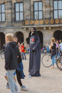 Amsterdam, Hollanda, Temmuz 2019: Ölümünde bir tırpofon ve ağzında sigara olan aktör, yaşayan heykel Amsterdam'ın merkezindeki Baraj meydanında sigara içmenin tehlikeleri konusunda uyardı 