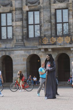 Amsterdam, Hollanda, Temmuz 2019: Ölümünde bir tırpofon ve ağzında sigara olan aktör, yaşayan heykel Amsterdam'ın merkezindeki Baraj meydanında sigara içmenin tehlikeleri konusunda uyardı 