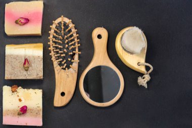 otlar ve gül tomurcukları ile el yapımı çok renkli sabun, tarak, havlu, ayna, siyah bir arka plan üzerinde yüz fırçası. Yüz ve vücut tedavileri için spa seti kiti düz yatıyordu istagram tarzı