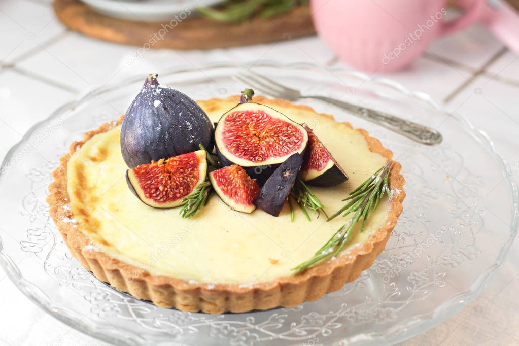 gorgeous round french classic homemade shortcake pastry dough vanilla custard tart cake decorated with figs and rosemary on glass stand near with retro fork on grey table cloth. Insta food photo style