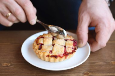 Gri kazaklı adam kışın kahve dükkanında siyah lungo americano kahvesi içer ve ahşap masada beyaz tabakta Amerikan ev yapımı vişneli turta yer. Sonbahar ruh hali instagram biçimi