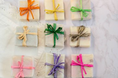 El yapımı organik sabun hediye balmumu ambalaj kağıdında mermer yüzeyinde çok renkli eko rafya kurdeleleri ve metin için yeri var. Hediye sabunu düz 2 numaralı perdede yatıyordu.