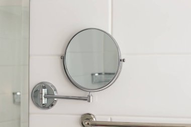Otel spa evinin duvarında asılı duran yuvarlak büyüteç aynası beyaz fayansların üzerinde. Banyo lüks iç mekan.. 