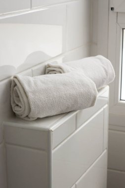 Otel spa evinin banyosunda, duvarında beyaz fayanslar olan iki rulo beyaz havlu vardı. Banyo lüks modern iç mekan.