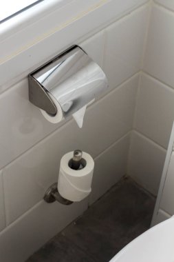 Otelin banyosunda beyaz fayanslar ve duvarında tuvalet kağıdı olan beyaz tuvalet kağıdı sarkıyor. Banyo lüks iç mekan. 