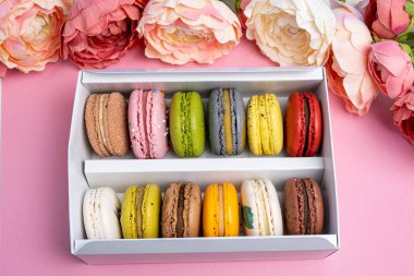 Pembe kutlama partisinde hediye kutusundaki renkli modern badem kurabiyeleri romantik parti, pion çiçekleri, saten kurdele, bir sürü çeşit makaron. Yumuşak düz üst görünüm