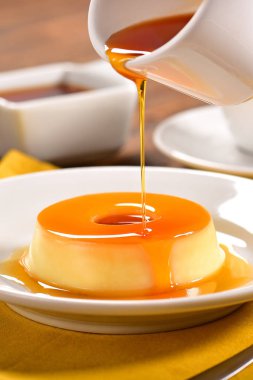 Vanilya pudim dekore edilmiş sahnede karamel sos ile