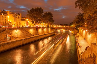 Yavaş çekimde Seine nehri üzerinde Akşam gezisi ve paris şehir merkezinde gece saatlerinde Ile de la Cite dolgu boyunca asılı insanlar, Fransa