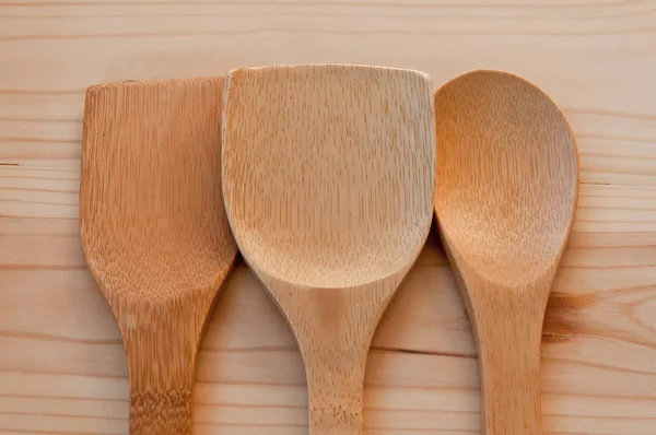 Background of kitchen utensils. Wooden bamboo spoons on a background of pine boards. Necessary accessories in the kitchen.