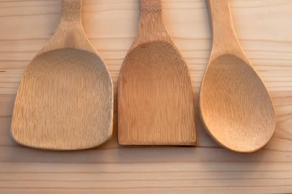 Background of kitchen utensils. Wooden bamboo spoons on a background of pine boards. Necessary accessories in the kitchen.