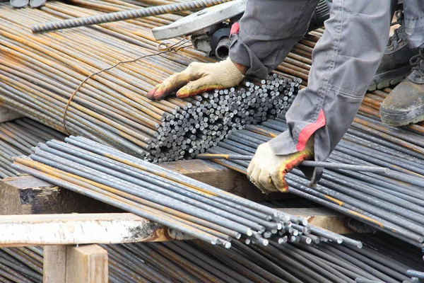 Worker makes blanks from rebar. Production of parts for concrete work during the construction of the building.