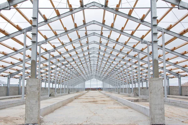 Wooden beams on a metal frame. Construction of agricultural buildings. The construction of the barn metal frame. The metal frame is made from galvanized metal. Metal beams are protected against corrosion.