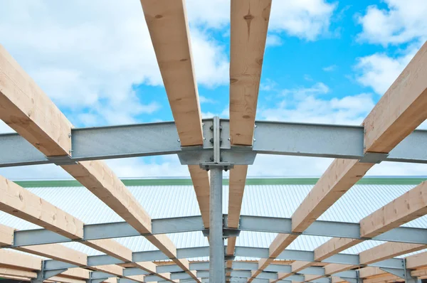 Wooden beams and metal frame of the new building. The use of two materials in construction. Wood and metal at a construction site.