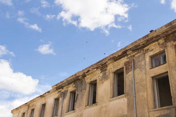 The facade of an old brick house on a background of blue sky on a sunny day