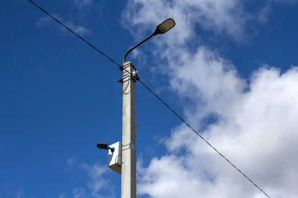 The LED street light is lined with a beautiful blue sky in the background with a video camera mounted on a pole. Video surveillance system.